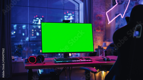 Gaming at Home: Empty Gaming Station with Player's Personal Computer with Green Screen Chroma Key Display Standing on a Wooden Desk in Stylish Loft Apartment with Neon Lights. 