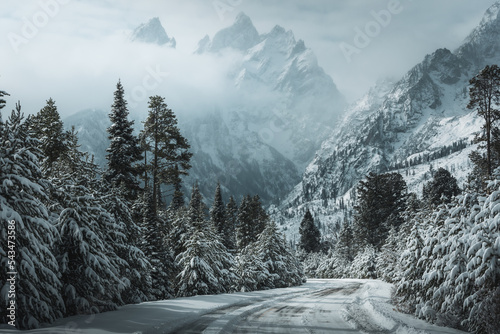 Tela Snowy road in Wyoming leading to the Grand Teton mountains covered in clouds wit