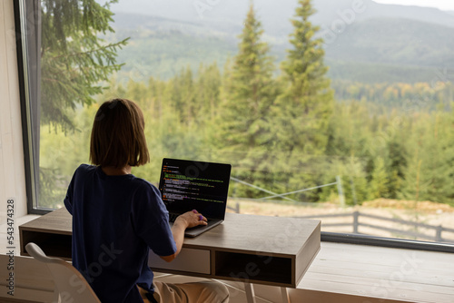 Woman works on laptop remotely in house on nature #543474328