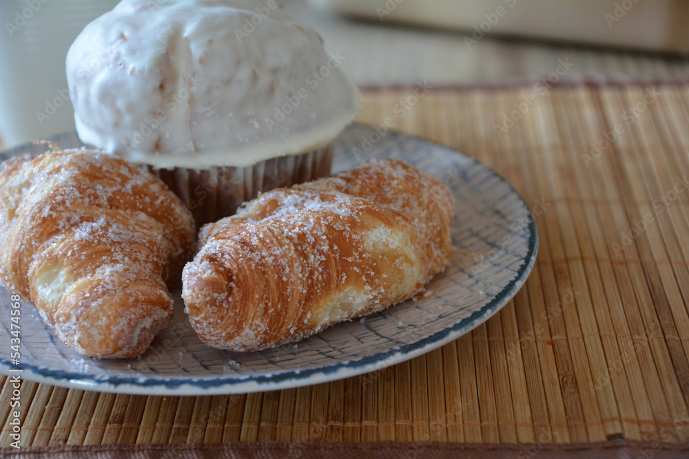 Freshly baked croissants with sugar and muffin with white chocolate. 