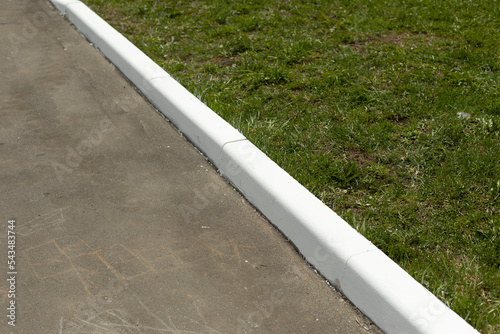 Painted curb. White curb on road. Landscaping in city. photo