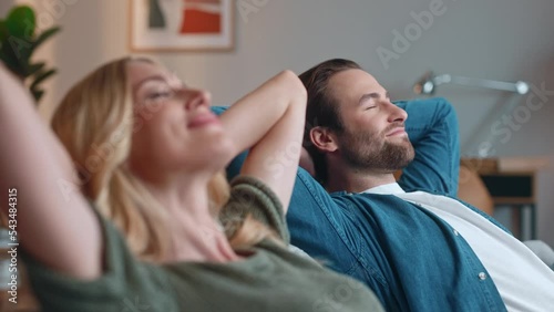 Cute man and pretty woman sitting and relaxing on sofa at home. Beautiful couple husband and wife lying on couch in living room having good time. Carefree relaxed lovely couple. Couple concept.