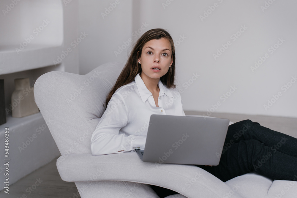 Amazed businesswoman in white shirt, black pants sitting in chair looking aside with wide opened eyes, shocked by news. Attractive student staring in surprise. Brunette young woman distant working. Amazed businesswoman in white shirt, black pants sitting in chair looking aside with wide opened eyes, shocked by news. Attractive student staring in surprise. Brunette young woman distant working.
