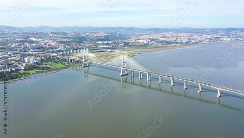 Cinematic aerial view of Vasco da Gama Bridge. Is a cable-stayed bridge flanked by viaducts that spans the Tagus River in Lisbon. It is the second longest bridge in Europe. Drone backward and pan left photo