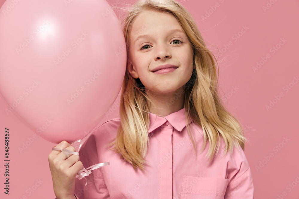 little girl, blonde, stands smiling happily with a pink balloon in her hands little girl, blonde, stands smiling happily with a pink balloon in her hands