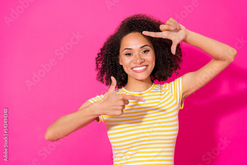 Close up photo of adorable young woman show fingers photo frame cadre wear stylish striped look isolated on vivid pink color background