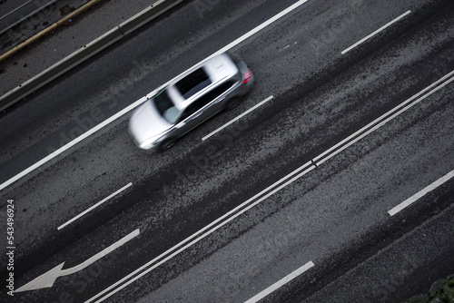 New modern silver car driving down highway from above on black wet asphalt in commuting and rush hour concept © Nicholas