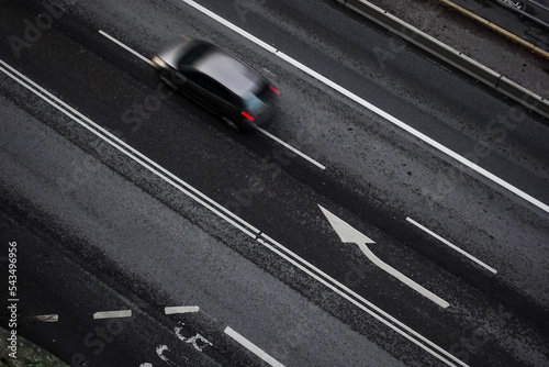 New modern black car driving down highway from above on black wet asphalt in commuting and rush hour concept © Nicholas