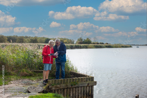 Foto Middle aged couple studying their map as they walk by the Norfolk Broads in East Anglia UK enjoying the sunny Autumn weather and exercising together