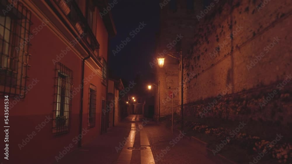 Narrow street with vintage buildings and bright lanterns in old Italian town. Ancient architecture and illuminated road in late evening
