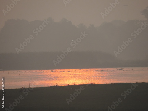 An evening sky , unique natural creature, plants and trees midow, reflection of the goden color sun in the lake water  photo