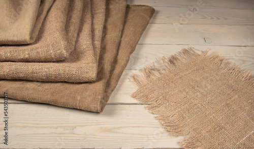 A stack of coarse peasant cloth - burlap and a tarpaulin on a wooden table. Rustic style image