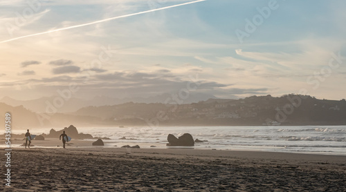 Two surfers at sunset on Meron beach  in San Vicente de la Barquera  Cantabria. Spain