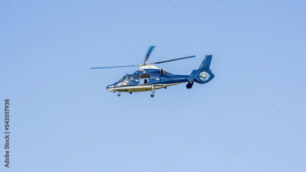 A British SAS Special Air Service Dauphin helicopter hovering low over woodland on a military training exercise, blue summer sky, Wiltshire UK