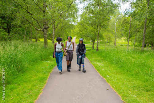 Fényképezés Three black non binary friends strolling through the park.