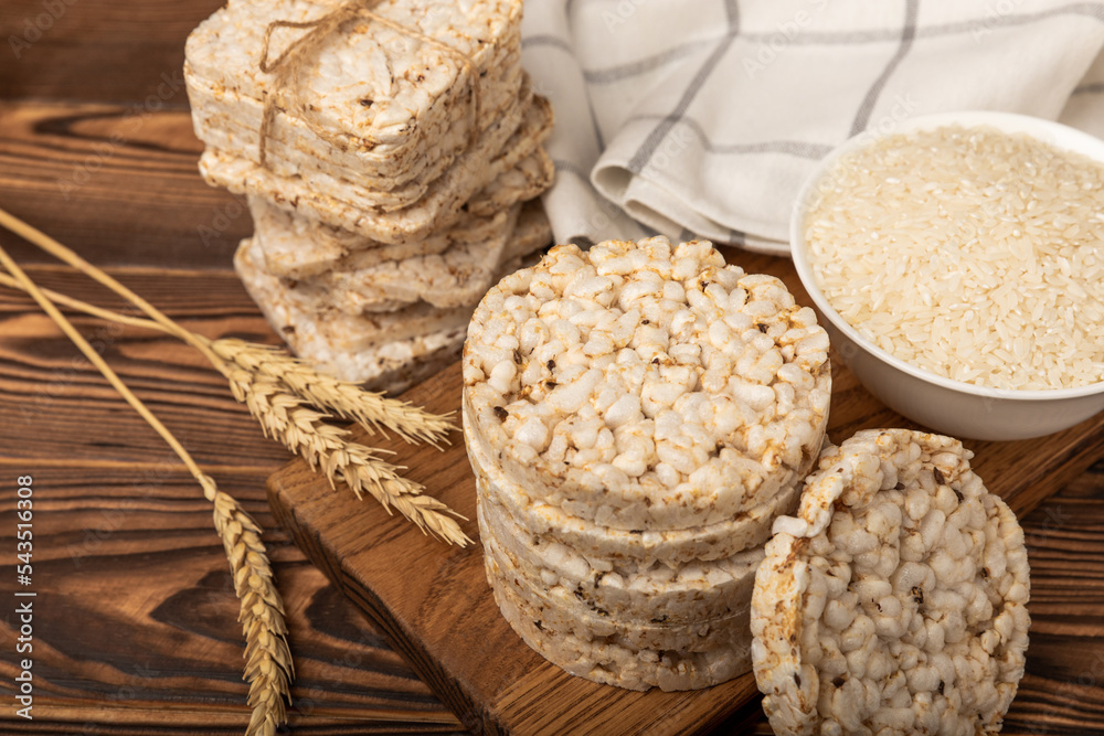 Round rice cakes and a plate of rice on a brown wooden table. Crispbread.Puffed rice bread. diet crispy round rice cakes.Place for text. Place for copy. Healthy food. dietary product.