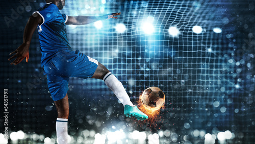 Football scene at night match with player kicking the ball with power photo
