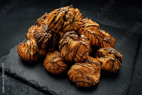 Profitrolls with chocolate on a dark background photo