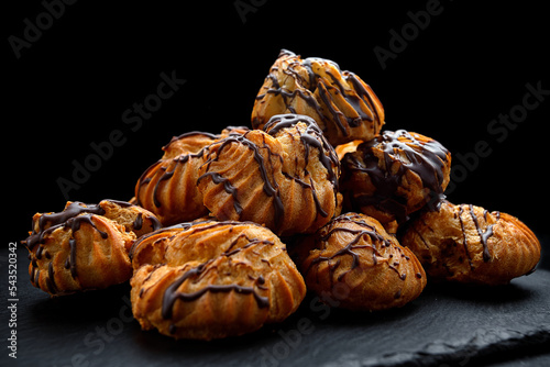 Profitrolls with chocolate on a dark background photo