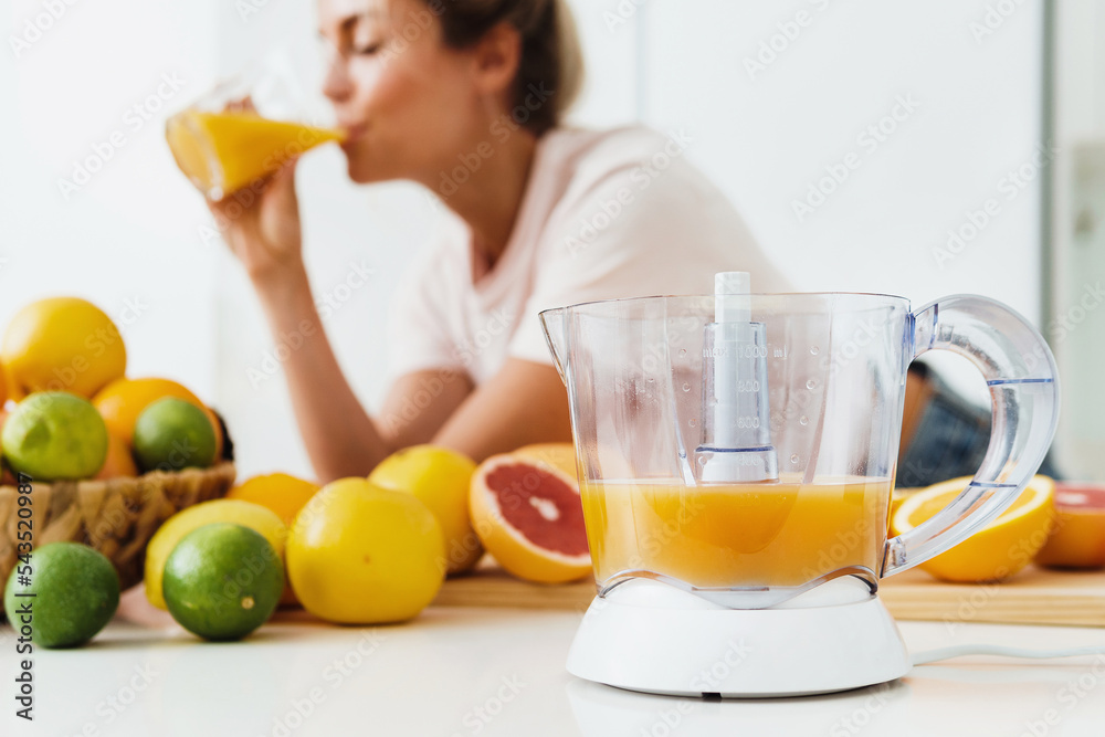 Citrus juicer and woman which drinking freshly squeezed homemade orange juice Citrus juicer and woman which drinking freshly squeezed homemade orange juice