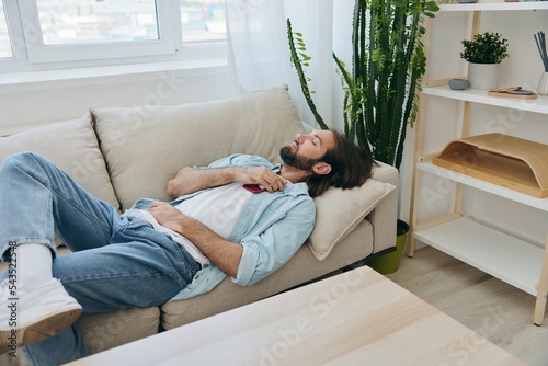A man sleeping on the couch during the day is tired and relaxed after stress and feeling bad. Stress at work, poor sleep and health problems