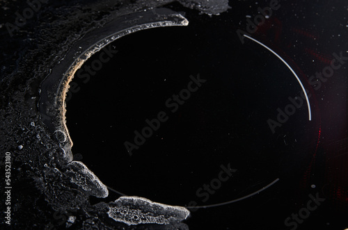 Ceramic kitchen stove burn damage marks and dry saline water splashes left after spillover from cooking pasta. Closeup shot