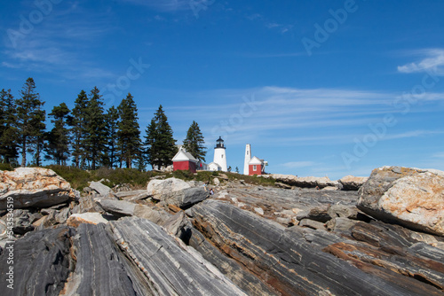 Lighthouse off the coast of Maine with beautiful striated rocks in foreground