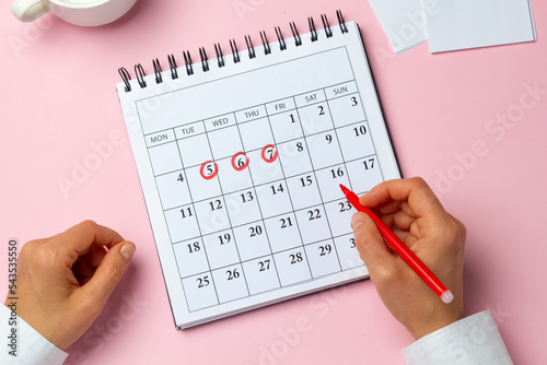 The concept of the menstrual cycle, period. The woman marks the days on the calendar. photo