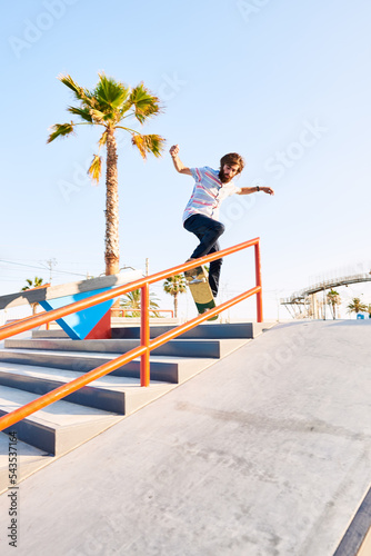 Bearded skater rolling on railing