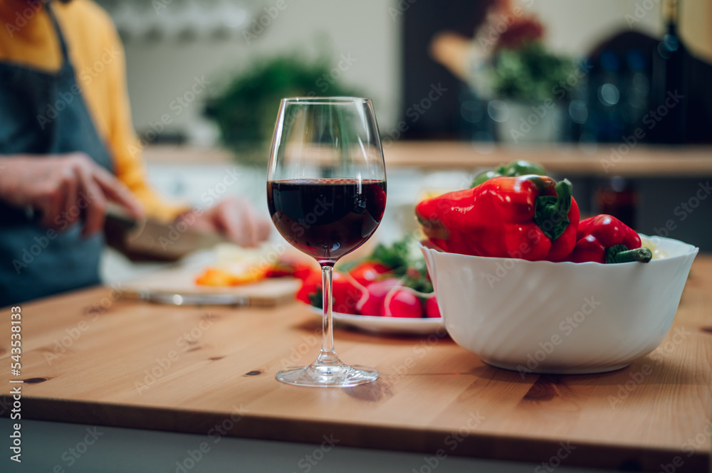 Naklejka premium Red wine in a glass standing on a kitchen counter