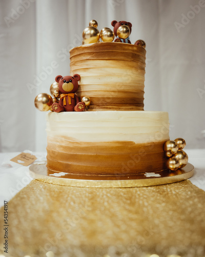 a decorated golden brown two tiered cake decorated with bears sits on a table