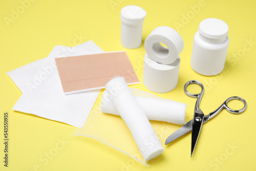 White bandage rolls and medical supplies on yellow background