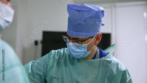 Concentrated surgeon working hard during operation. Portrait of an experienced doctor focused on his work. Blurred backdrop. photo