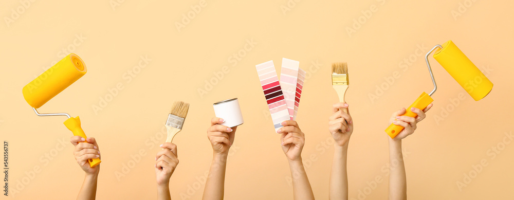 Female hands with painter's tools on beige background
