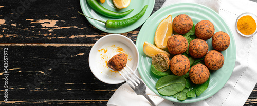 Plate with tasty falafel balls and sauce on dark wooden table photo