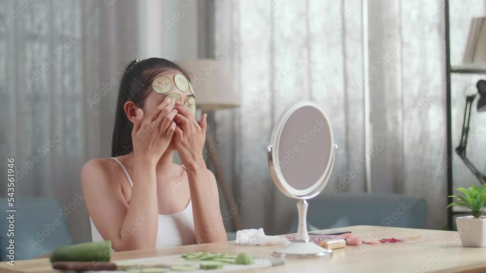 Beautiful Young Asian Woman Looks In The Mirror And Gets A White Facial Mask With Cucumbers While Taking Care Of Her Skin At Home
Beautiful Young Asian Woman Looks In The Mirror And Gets A White Facial Mask With Cucumbers While Taking Care Of Her Skin At Home