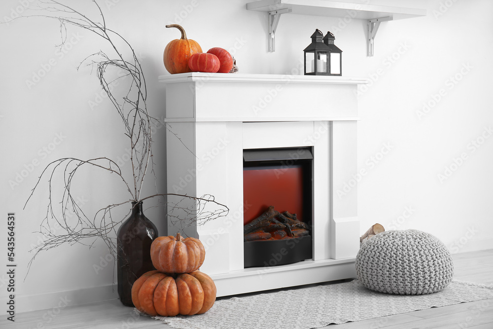 Fototapeta premium White fireplace with Halloween pumpkins and lanterns in light living room