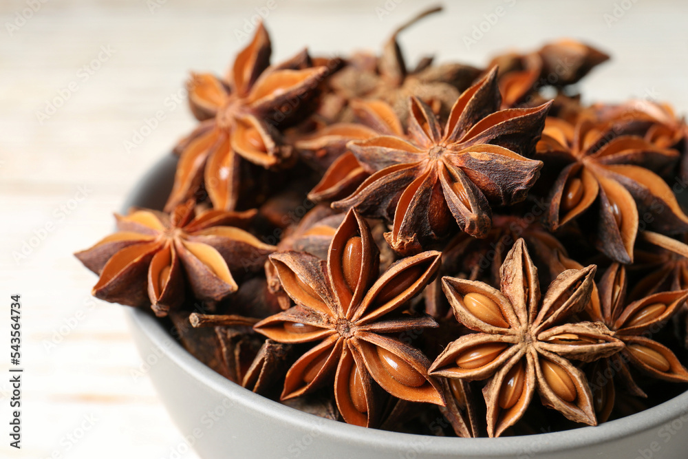 Many aromatic anise stars in bowl, closeup