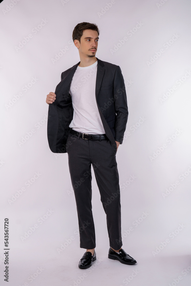 Portrait of happy handsome young man in suit posing on isolated background