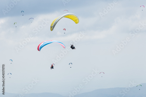 A paraglider flight in a blue sky with clouds, paragliding competition