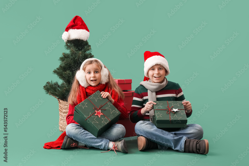 Little children with presents and Christmas tree sitting on green background Little children with presents and Christmas tree sitting on green background