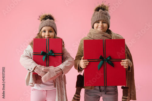 Little children with Christmas presents on pink background