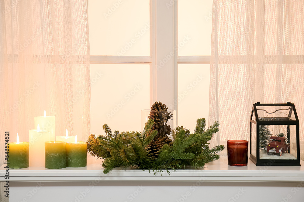 Christmas wreath with burning candles on mantelpiece near window Christmas wreath with burning candles on mantelpiece near window