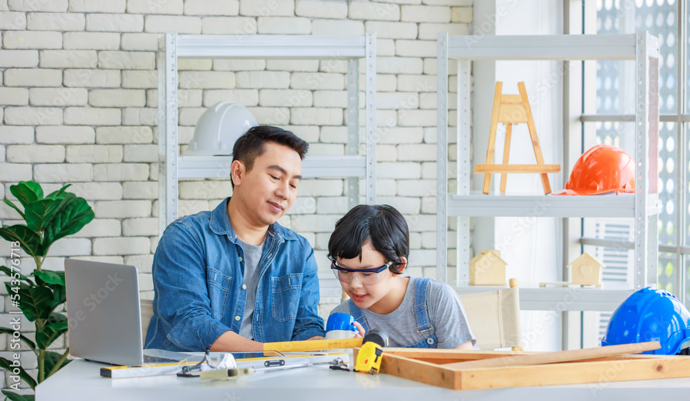 Asian professional male carpenter woodworker engineer architect dad in jeans outfit teaching young son with safety gloves goggles learning building tools and equipment in housing construction site Asian professional male carpenter woodworker engineer architect dad in jeans outfit teaching young son with safety gloves goggles learning building tools and equipment in housing construction site