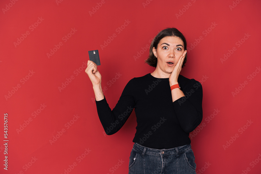 Lady in shock holding credit card in her hand against red background. Lady in shock holding credit card in her hand against red background.