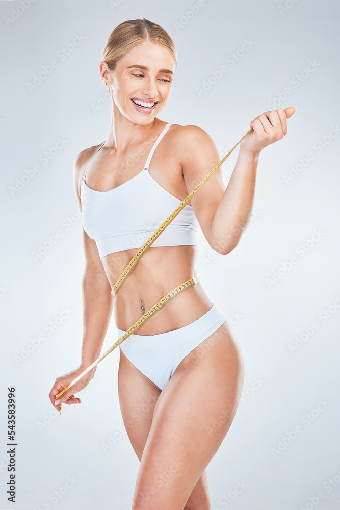 Weightloss, smile and woman with a tape for progress, measurement and check against a grey studio background. Happy, wellness and young model measuring her waist for beauty, diet and fitness Weightloss, smile and woman with a tape for progress, measurement and check against a grey studio background. Happy, wellness and young model measuring her waist for beauty, diet and fitness