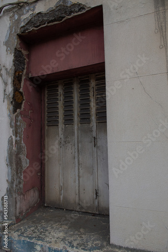 Vieille fenêtre fermée par un volet pliant en fer, rouille, mur vétuste