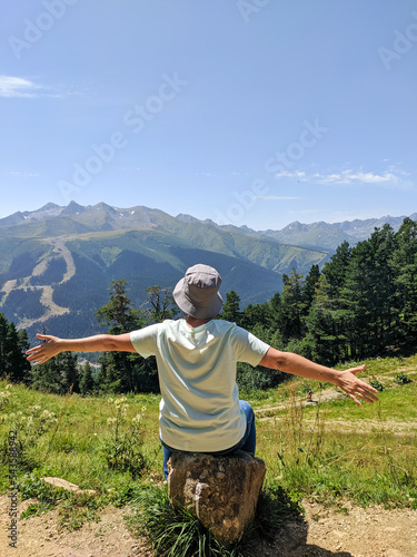 Arkhyz, Karachay-Cherkessia, Russia - August 21, 2022: Beautiful view of the Caucasian mountains and coniferous forest in the resort area of Arkhyz. Woman admires the beauty of nature. Vertical