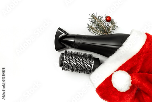 Christmas composition. Hairdressing tools and a spruce branch on a white background, hair dryer, comb. Template for a postcard or information about a hair salon. Flat lay, copy space