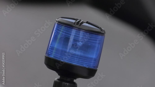 Blue rotating police light at the back of a motorbike and mounted on a telescopic pole. A traffic police officer with a motorcycle during a city inspection